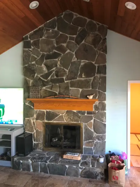 Before: the original dark stone fireplace and wood mantel