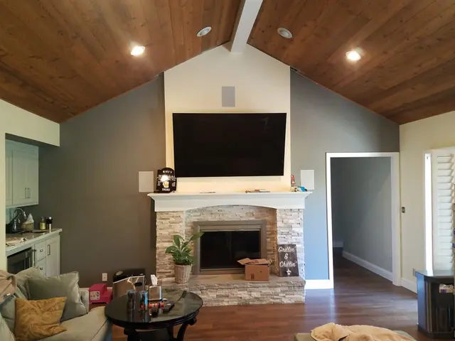 Refaced fireplace with light stacked stone under a vaulted wood ceiling