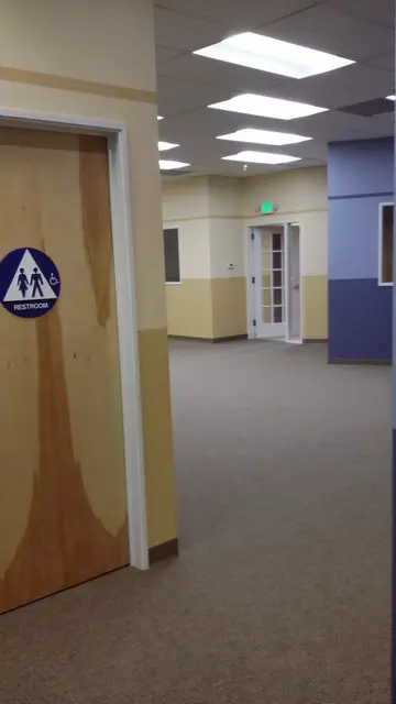 After: hallway with blue and tan walls and a restroom door at Huntington Learning Center in Danville