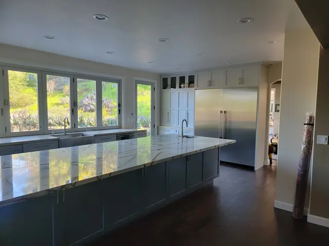 Long blue island and stainless refrigerator in the remodeled kitchen