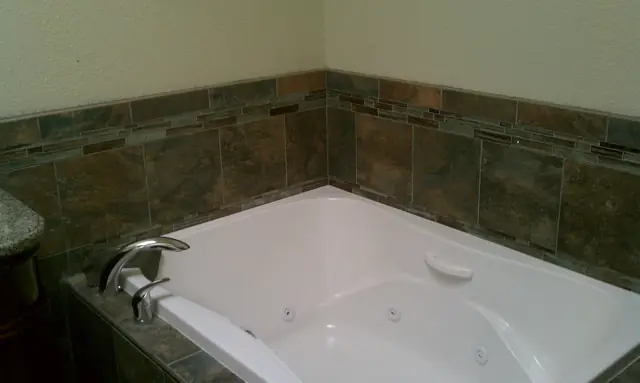 Jetted tub with a stone tile surround in the remodeled Livermore bathroom