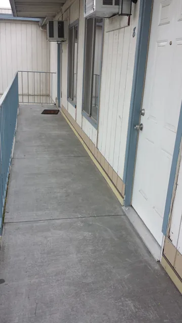 After: the finished second-floor walkway at the Manteca apartments, a clean grey walking surface along the doors