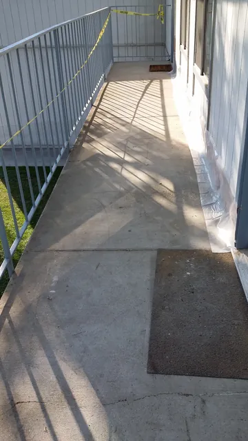 Before: the old, worn walkway surface with a mat outside the Manteca apartment doors
